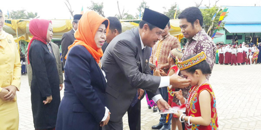 SIMBOLIS : Pj Walikota Zairin Zain saat memberikan buku kepada murid dan orang tua disela-sela acara Hardiknas Rabu (2/5) pagi tadi di halaman SMPN 22 Jl Pahlawan Samarinda.