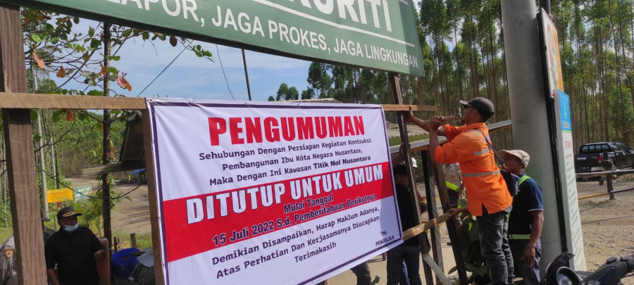 Petugas di pos penjagaan memasang spanduk pengumuman ditutupnya kawasan titik nol IKN untuk umum. (Ist)