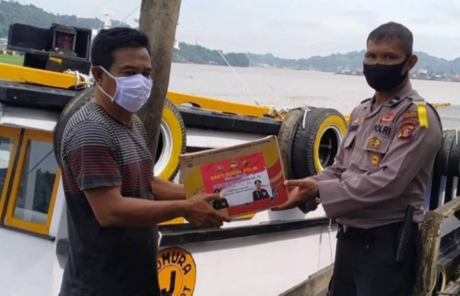 Anggota kepolisian saat membagi sembako kepada buruh pelabuhan (Foto: Claudius Vico/ Korankaltim.com)