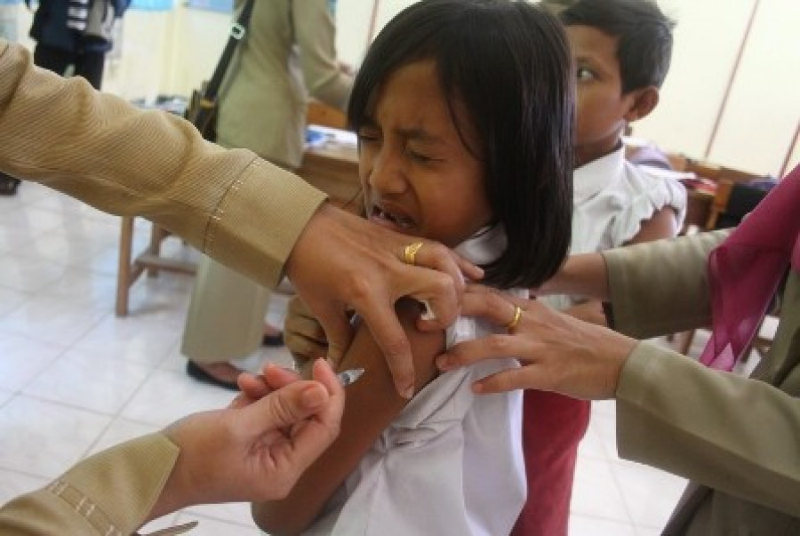 PETUGAS kesehatan menyuntikan Difteri Tetanus (DT) kepada seorang pelajar SD ketika proses imunisasi DT.