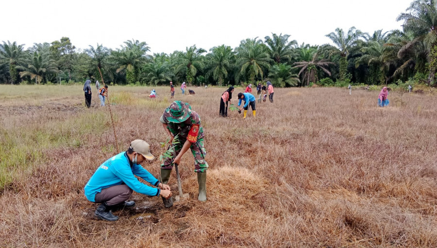Dzikri Zulkarnain (Baju Biru) bersama Babinkamtibmas dan Warga saat gotong Royong penanaman Bibit Durian. (Foto : Dwi Cahyo / Korankaltim.com)