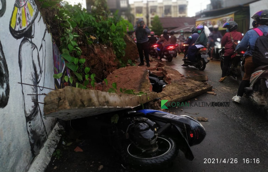 Akibat tanah bergeser dua motor yang terparkir di Jalan Anggur tertimpa tembok, hingga mengakibatkan motor mengalami kerusakan parah Senin (26/4/2021) sore tadi. (Foto: Nancy/korankaltim.com)