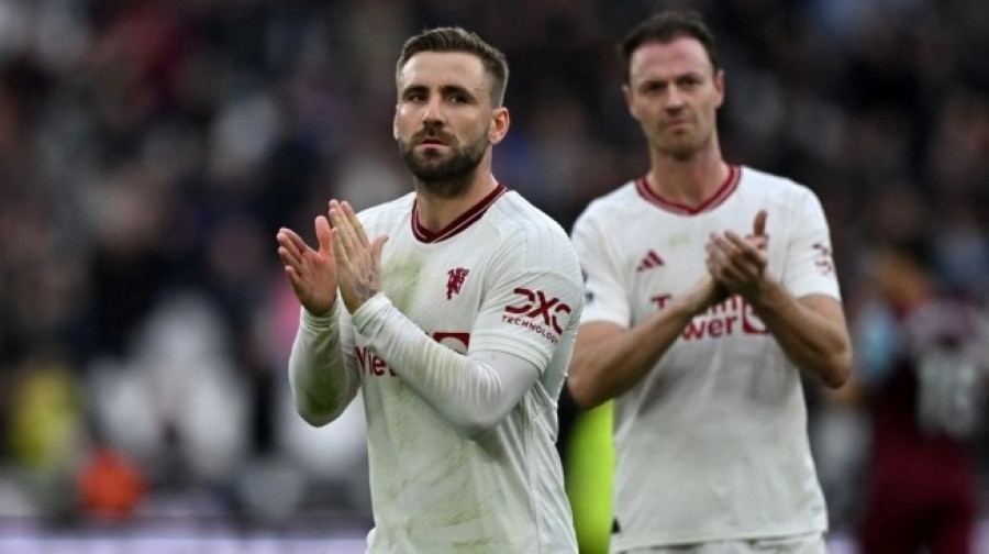 Pemain Manchester United, Luke Shaw (kiri) dan Jonny Evans memberikan aplaus pada suporter usai laga Liga Inggris kontra West Ham United di London Stadium, Sabtu (23/12/2023) malam WIB. (Foto: AFP)