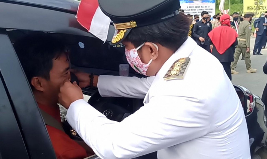 Bupati Abdul Gafur Mas’ud membagikan dan memasangkan masker secara langsung kepada masyarakat. (Erwin/Korankaltim.com)