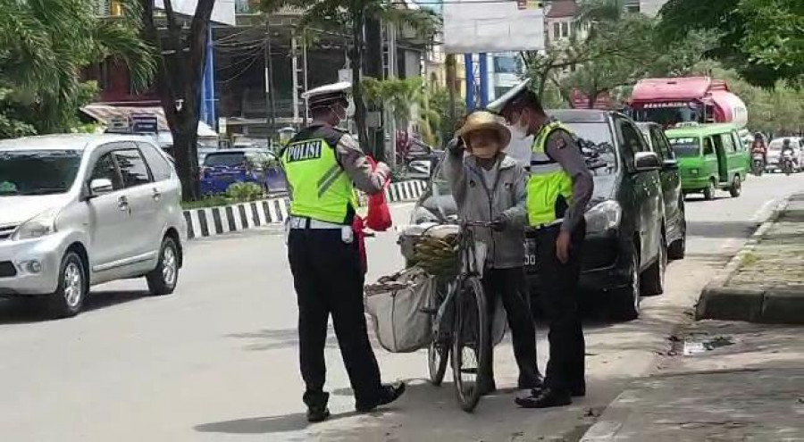 Petugas Satlantas Polresta Samarinda saat membagikan sembako kepada warga yang melintas.(Foto:Nancy/korankaltim.com)