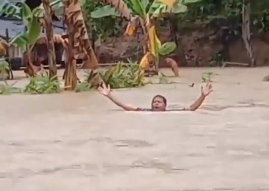 Tangkapan layar video yang beredar di media sosial, seorang pria sedang berjalan di tengah-tengah banjir di Sebulu. (Foto: istimewa)