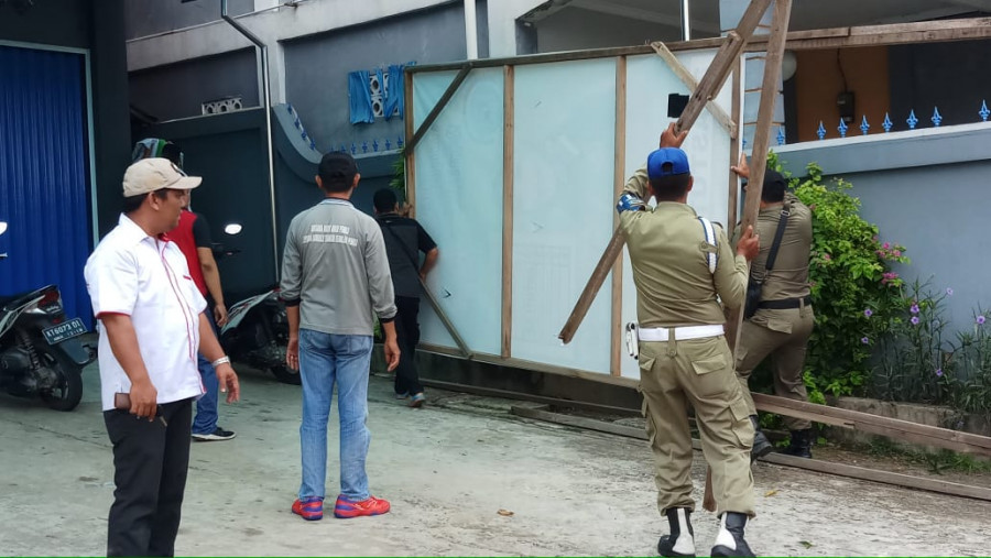 SULIT - Beberapa APK ada yang sulit dilepas dan tampak petugas Satpol PP menurunkan baliho caleg yang terpasang. (Cholisoh/KoranKaltim.Com)