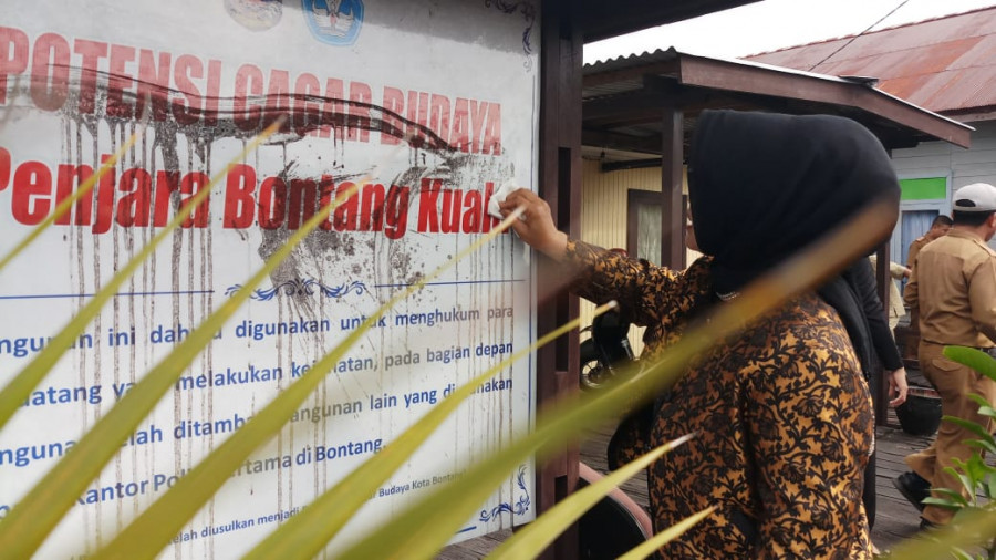 Wali Kota Bontang Neni langsung membersihkan papan potensi cagar budaya penjara, yang masih ada di Bontang Kuala ( Foto: Olis / korankaltimcom)
