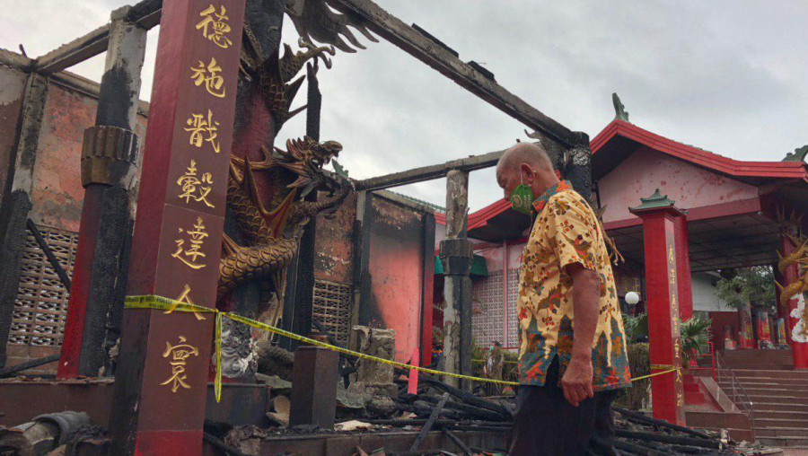 Salah satu jamaah klenteng Guang De Miao Balikpapan saat melintas di puing-puing klenteng (Foto: Yudi Hadi/korankaltimcom)