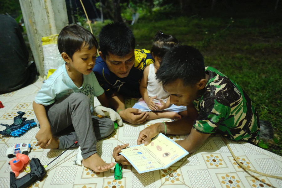 Personel satgas TMMD mengajari anak- anak membaca ( Humas Kodim)