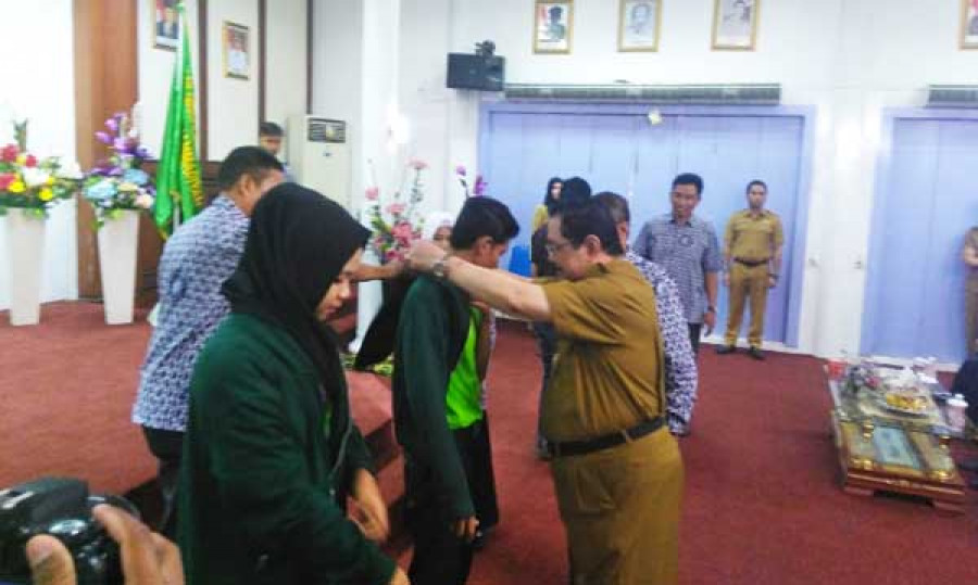 Bupati Paser memasangkan jaket seragam KKN kepada salah satu Mahasiswa KKN STIPER Muhammadiyah Tanah Grogot penanda dimulainya masa KKN