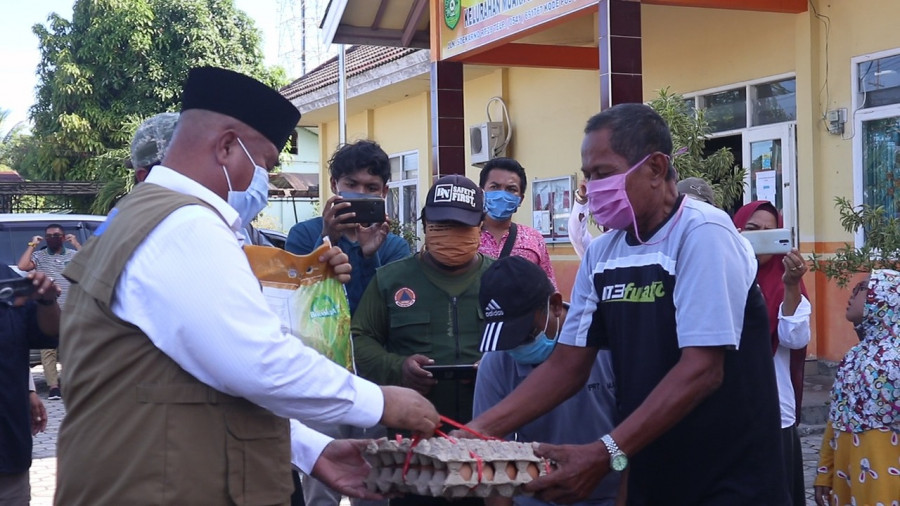 Bupati Kukar Edi Damansyah saat menyalurkan langsung bantuan sembako kepada salah satu warga Muara Jawa. (Foto: Reza Fahlevi/korankaltimcom)