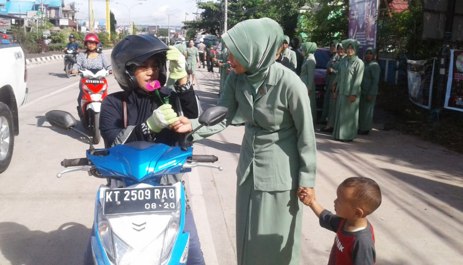 Ibu persit kodim 0909/sgt melakukan tebar bunga kepada semua wanita yang melintas di jalan raya
