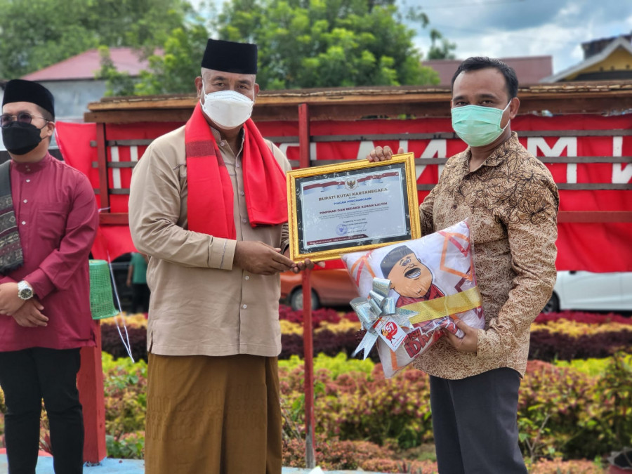 Direktur Koran Kaltim Desman Minang menerima penghargaan dari Bupati Kukar Edi Damansyah. (Foto: Heri/Korankaltim.com)
