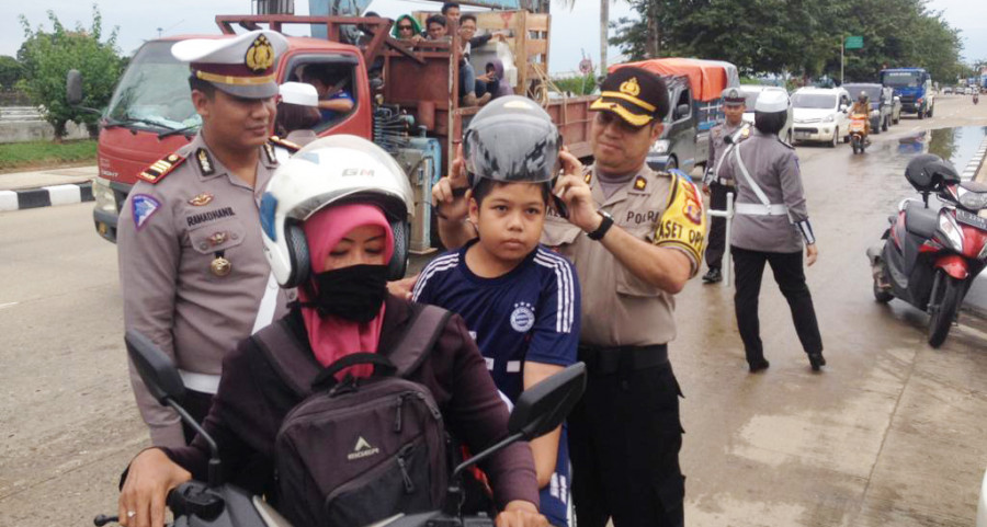 Kasatlantas Polres Kukar, AKP Ramadhanil bersama personilnya memasangkan helm kepada anak-anak saat giat oprasi keselamatan 2019 di Jln Wolter Monginsidi, Senin (29/4/2019)