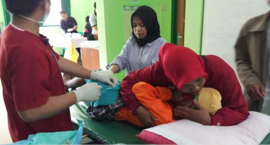 Peserta sunat menahan sakit saat tim medis tentara TMMD memotong ‘burungnya’, diacara sunatan massal dalam rangka TMMD ke-102, di Polkes Kodim 0908/BTG, Selasa (11/7/2018)