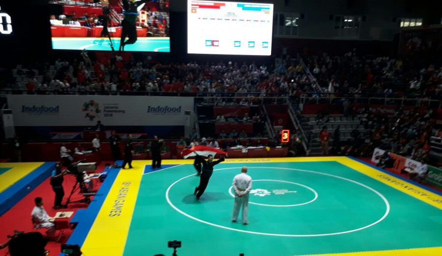 Iqbal Chandra Pratama mengibarkan sang Merah Putih usai memastikan dirinya menjuarai pencak silat kelas 60-65 kg.