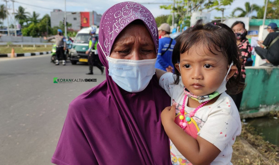Nenek Rehana menangis usai melihat Presiden Joko Widodo melintas sambil melambaikan tangan dari dalam mobil sambil menggendong cucu. (Foto: Yudi Hadi/ korankaltim.com)