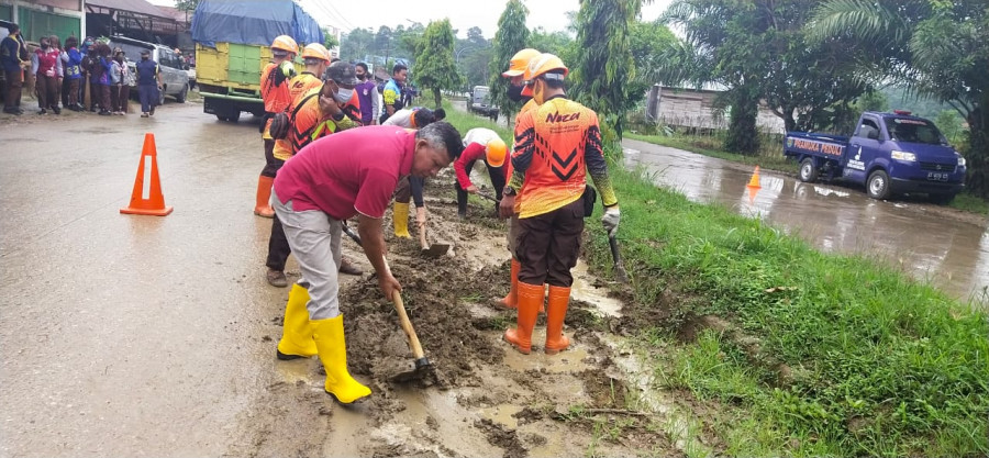 Camat Tenggarong Seberang, Suparman (baju merah) saat membersihkan jalan yang berlumpur di Jalur 2 Tenggarong Seberang. (Foto: Camat Tenggarong Seberang)