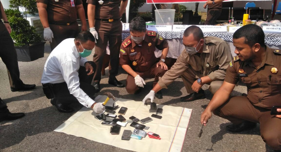 Kajari Tanah Grogot Syarif K memusnahkan ponsel dengan palu.