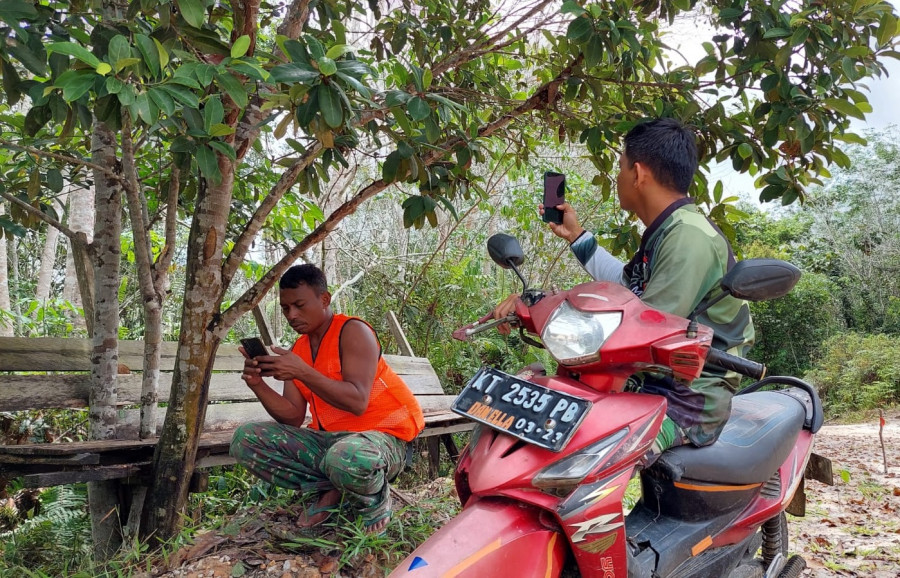 Anggota satgas TMMD, Serka Agus Indra dan Serda .Jumari harus mencari tempat untuk bisa berkomunikasi dengan keluarga karena tidak semua tempat ada sinyal. (Foto: Kodim 0912/KBR)