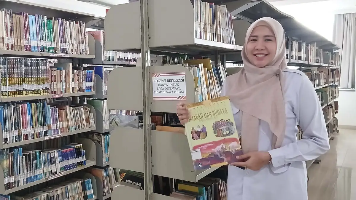 Kabid Layanan, Otomasi, dan Kerjasama DPK Kaltim, Sri Rezeki Marietha menunjukkan salah satu buku di area koleksi. (Yieli/KoranKaltim.com)